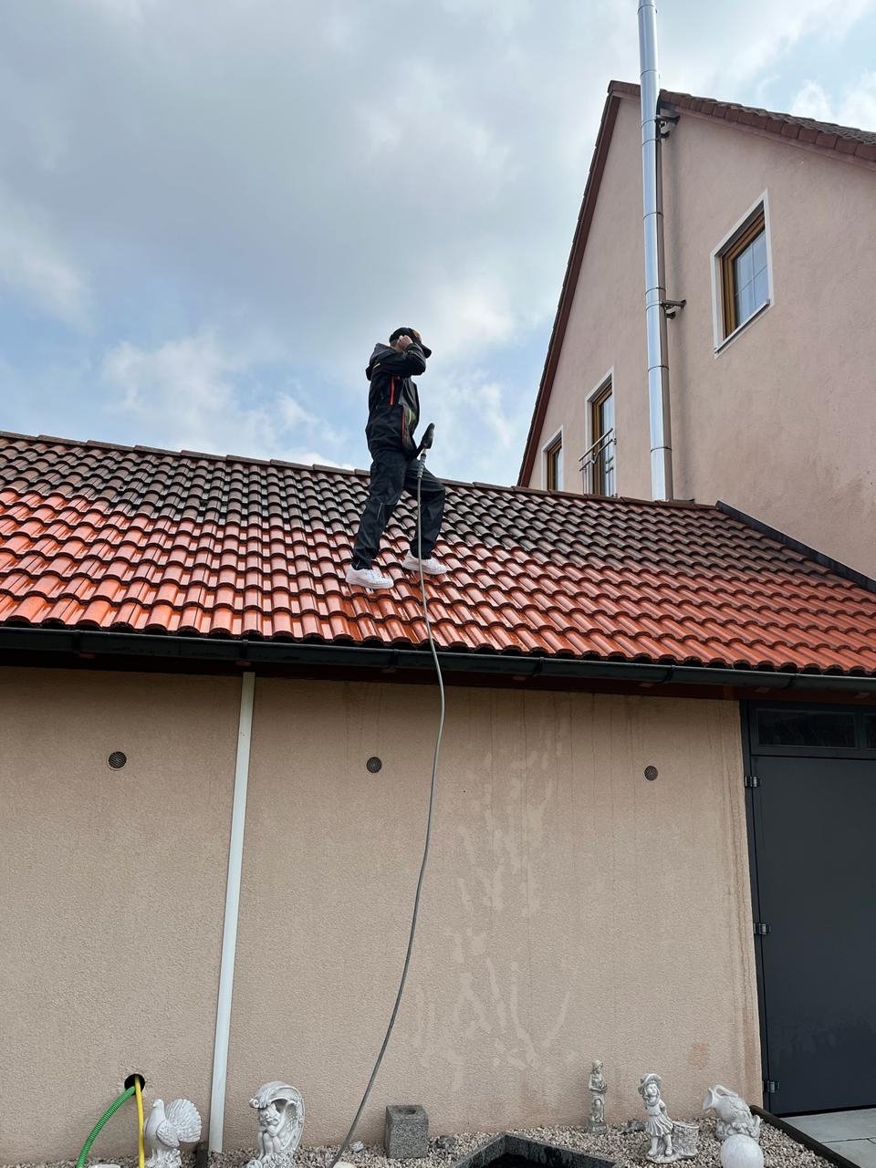 Dachreinigung: linke Dachhälfte frisch gereinigt in leuchtendem Orange, rechte Hälfte noch dunkel verschmutzt