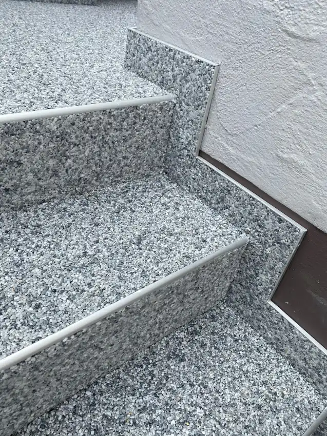 Steinteppich auf Außentreppe in Grau, fugenlos über Stufen und Sockelleisten